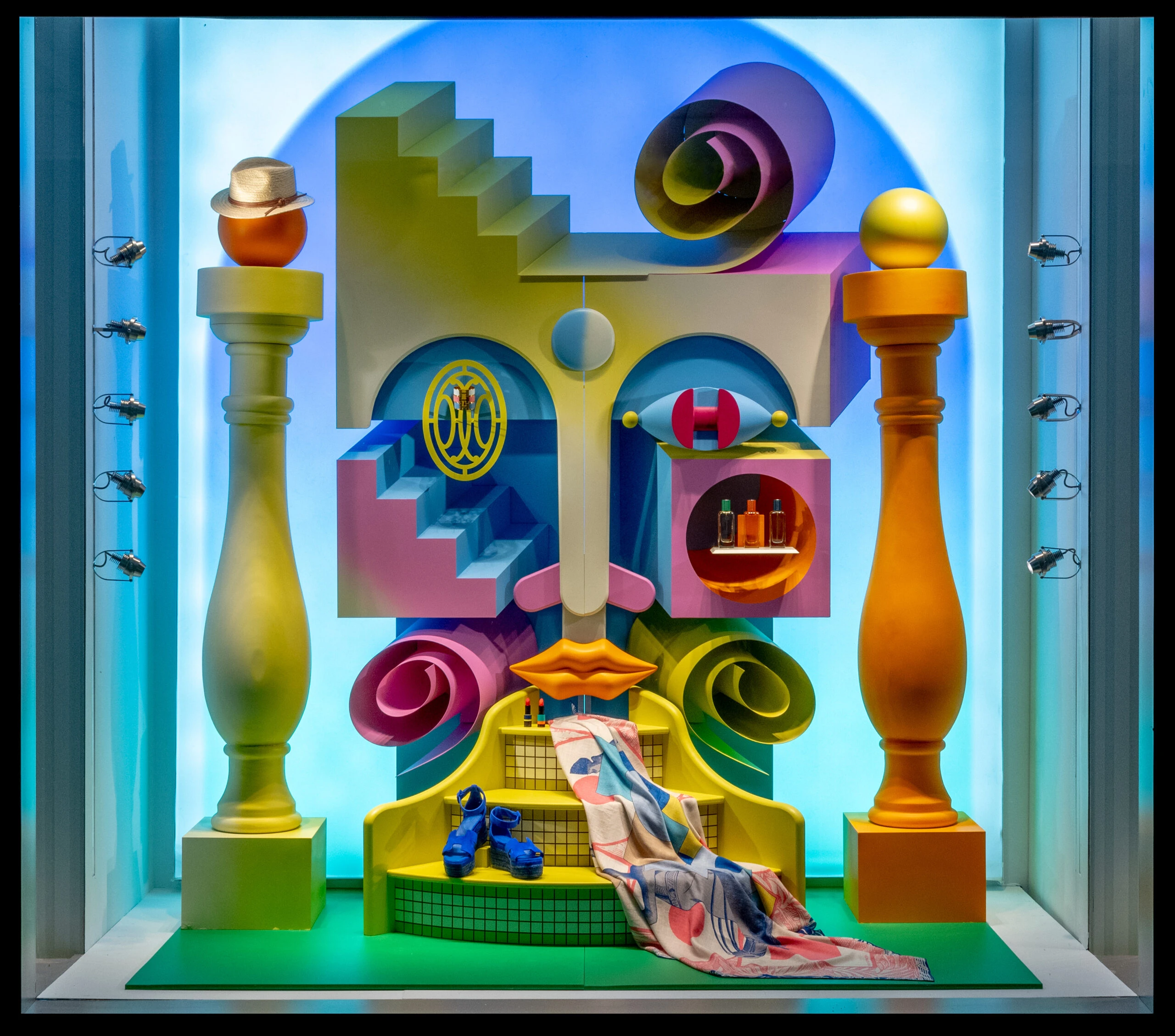 A window display of the Hermes storefront. In it, colorful 3D geometric shapes and pillars are arranged in a way to look like a face.